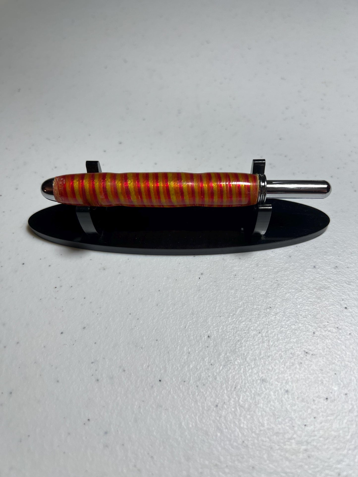 Reversible seam ripper with chrome finish in pink yellow and orange embroidery thread with clear resin