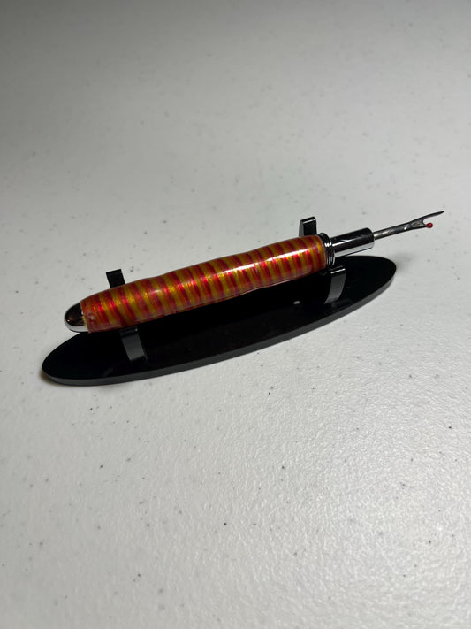 Reversible seam ripper with chrome finish in pink yellow and orange embroidery thread with clear resin